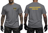 Front and back view of a charcoal t-shirt featuring the yellow Berufsfeuerwehr München logo on the chest and bold back text.