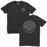 Classic black t-shirt featuring the Police Academy movie logo with a small left-chest emblem and a large circular back print displaying the badge design with the text POLICE ACADEMY and INTEGRITY KNOWLEDGE COURAGE.