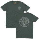 Classic dark green t-shirt featuring the Police Academy movie logo with a small left-chest emblem and a large circular back print displaying the badge design with the text POLICE ACADEMY and INTEGRITY KNOWLEDGE COURAGE.