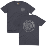 Classic navy t-shirt featuring the Police Academy movie logo with a small left-chest emblem and a large circular back print displaying the badge design with the text POLICE ACADEMY and INTEGRITY KNOWLEDGE COURAGE.