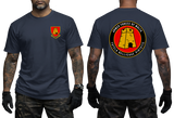 A man modeling a navy blue t-shirt, showing both the front and back views. The front features a small red and yellow military crest on the left chest.