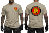 A man modeling a tan short-sleeve t-shirt, showing both front and back views. The front features a small red and yellow military-style crest on the left chest.