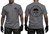 A man modeling a charcoal gray short-sleeve t-shirt, showing both the front and back views. The front features a small black shield crest on the left chest, and the back features a large black circular graphic with a parachute emblem and the text 'SPECIAL OPERATIONS FORCES AUSTRIA JAGOKOMMANDO'.