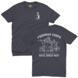 Two-view composite image of a navy t-shirt featuring Royal Danish Navy Frogman Corps (Frømandskorpset) graphics. The top view shows the front of the shirt with a small anchor, shield, and crown chest emblem and 'Frømandskorpset' text. The bottom view shows the back of the shirt with a large graphic of frogman commandos wading through water with rifles, 'Frogman Corps' heading, and 'Royal Danish Navy' text at the bottom.