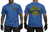 A man modeling a royal blue t-shirt, showing both the front and back views. The front features a small circular green and yellow emblem on the left chest.