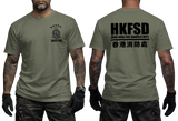 Front and back views of an olive green short-sleeve t-shirt worn by a model. The front features a small black HKFSD emblem on the left chest, and the back features a large black HKFSD logo with 'HONG KONG FIRE SERVICES DEPT.