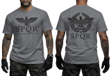 Two-view composite image of a dark grey t-shirt featuring Roman-inspired SPQR graphics. The left side shows the front of the shirt with a small emblem. The right side shows the back of the shirt with a large imperial eagle graphic and 'SPQR' text. The shirt is displayed on a male model with tattooed arms and tactical gloves.