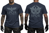 Two-view composite image of a navy t-shirt featuring Roman-inspired SPQR graphics. The left side shows the front of the shirt with a small emblem. The right side shows the back of the shirt with a large imperial eagle graphic and 'SPQR' text. The shirt is displayed on a male model with tattooed arms and tactical gloves.