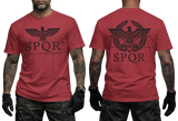 Two-view composite image of a red t-shirt featuring Roman-inspired SPQR graphics. The left side shows the front of the shirt with a small emblem. The right side shows the back of the shirt with a large imperial eagle graphic and 'SPQR' text. The shirt is displayed on a male model with tattooed arms and tactical gloves.