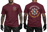 A man modeling a burgundy short-sleeve T-shirt shown from the front and back. The front has a small circular Merseyside Fire & Rescue Service logo on the left chest, and the back has a large matching logo with the words 'MERSEYSIDE FIRE & RESCUE SERVICE'.